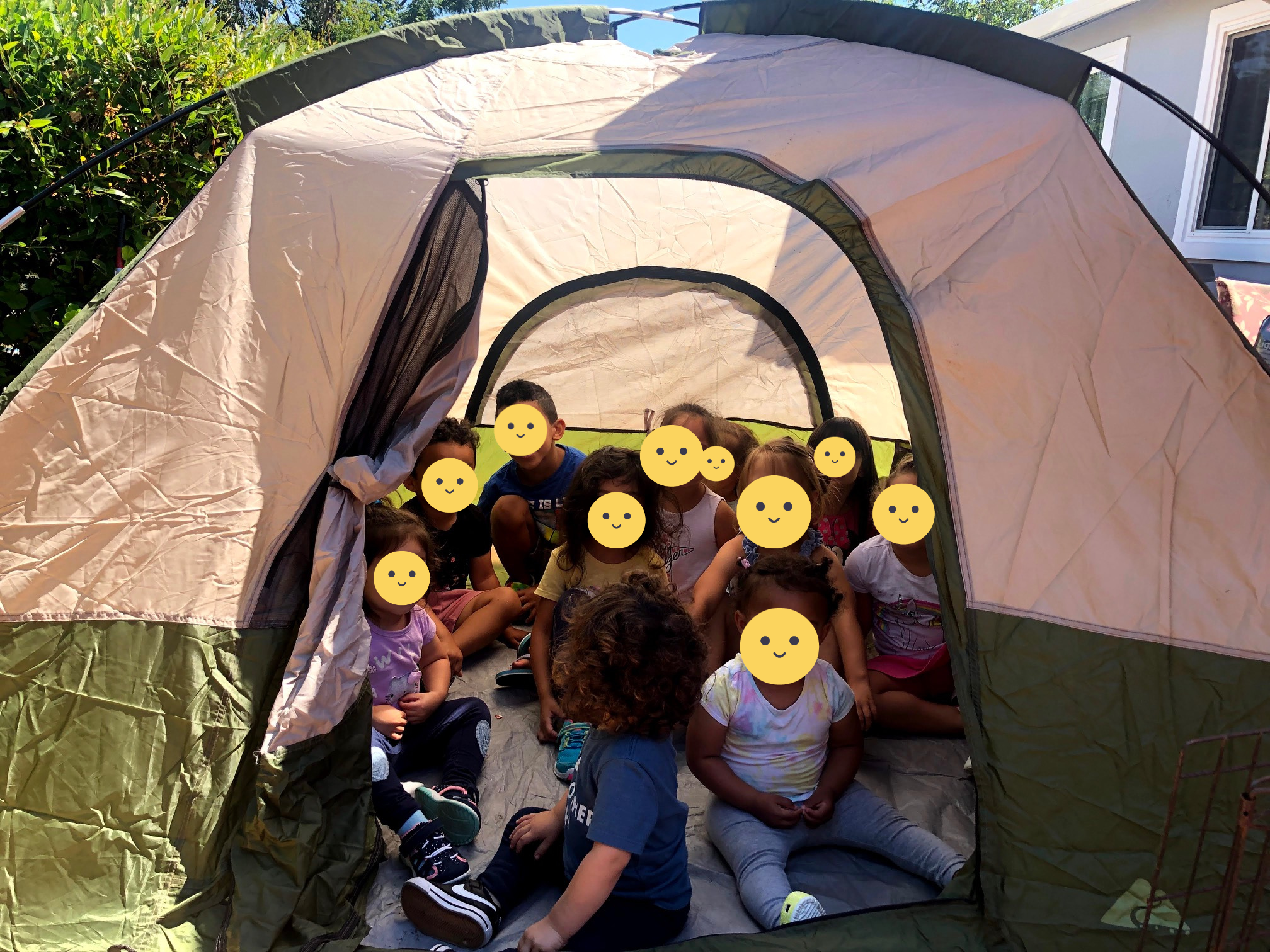 Children playing in a tent outside.